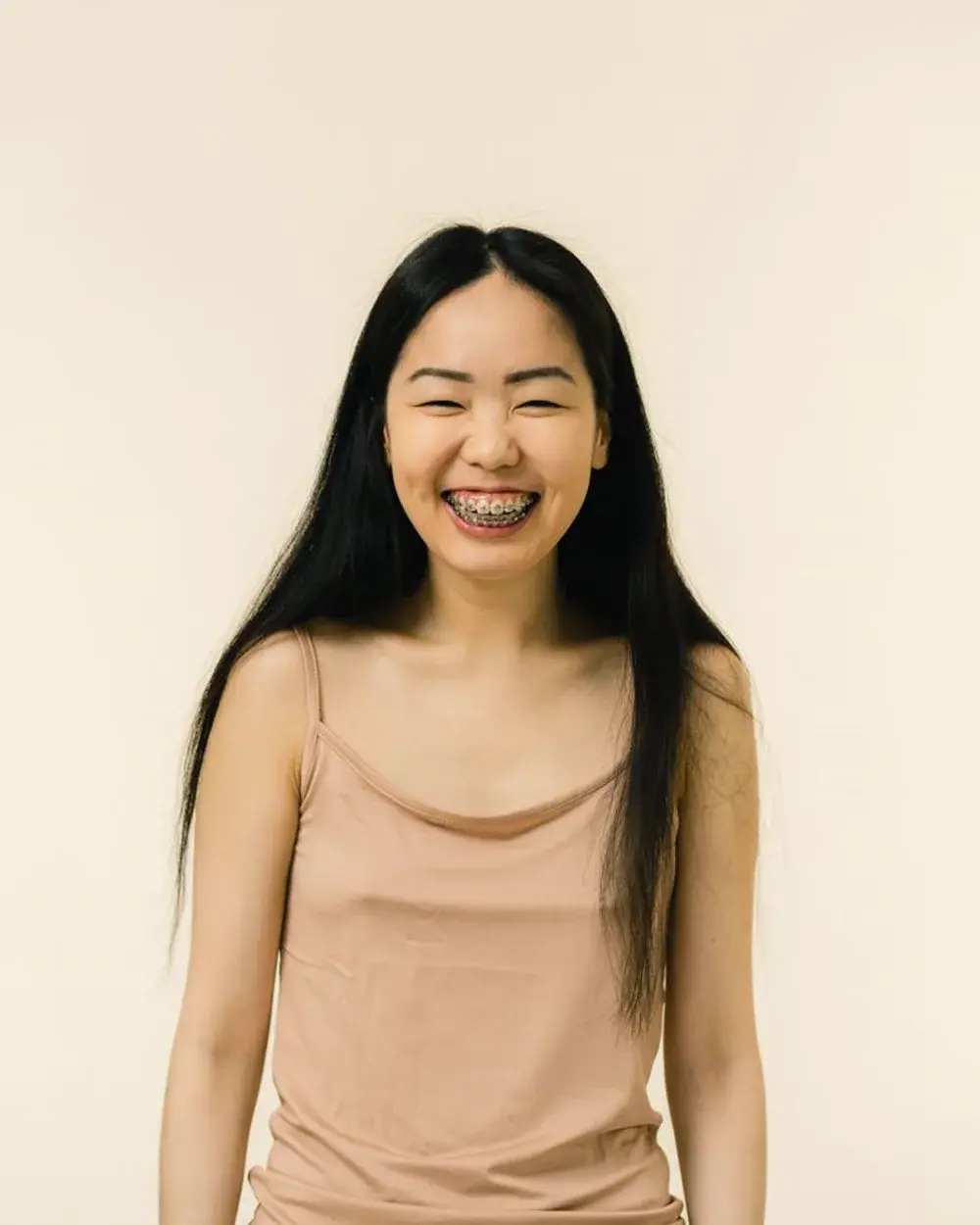 A young woman smiling, showing fixed orthodontic braces on her teeth