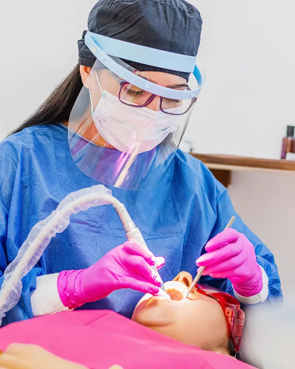A dentist in protective gear performing a surgical extraction